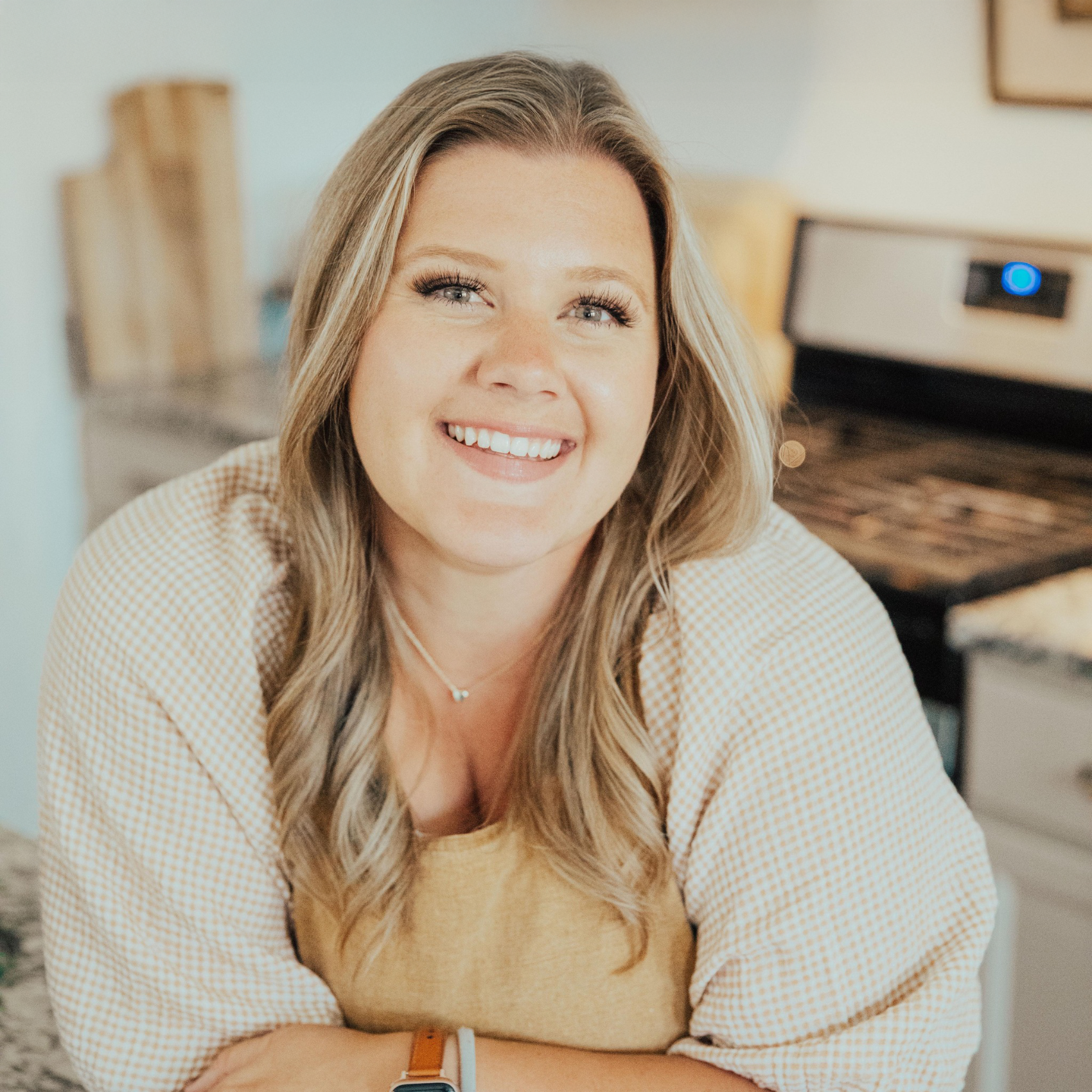 Woman in a kitchen wearing an apron, smiling.