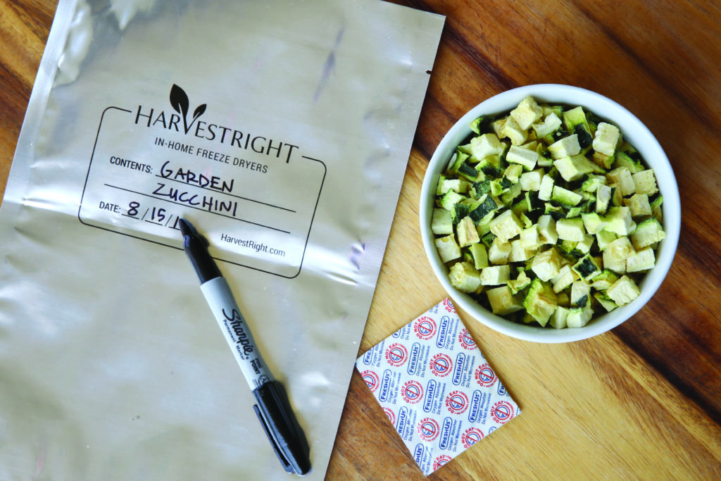 a Harvest Right mylar bag, a marker, an oxygen absorber, and chopped freeze dried zucchini