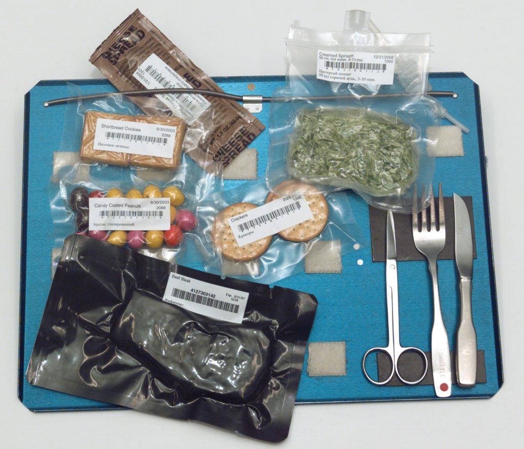 Packaged Astronaut food on a tray with eating utensils