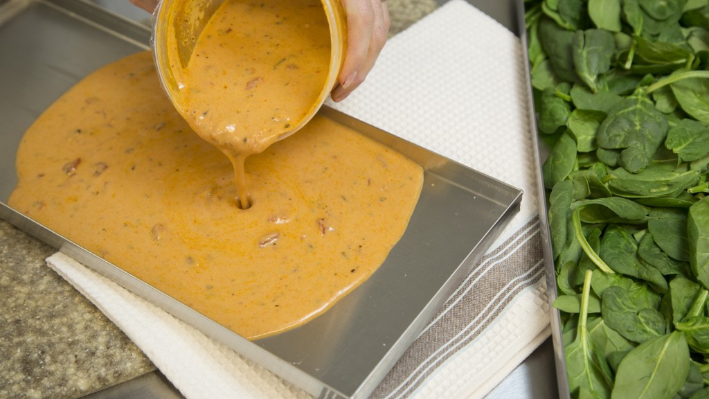 tomato soup being poured into a freeze dryer tray, basil in a freeze dryer tray