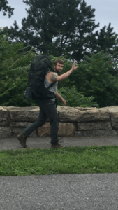 man wearing backpack, waving