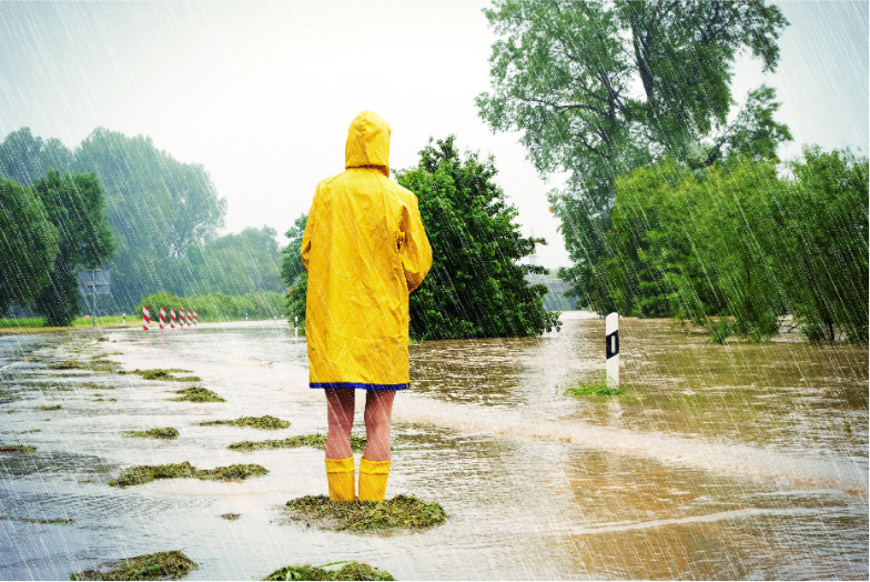 Person in yellow rain coat and boots standing in a flooded area